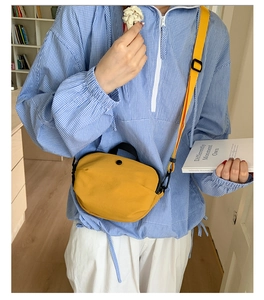 Photo lifestyle d'un sac bandoulière jaune en nylon avec poignées noires et sangle