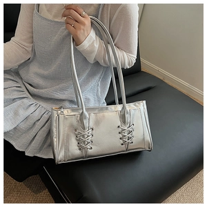 Détail du sac bandoulière argenté métallisé avec lacets décoratifs et finition brillante