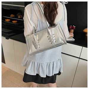 Détail du sac à bandoulière argenté avec laçage décoratif croisé et finition métallique