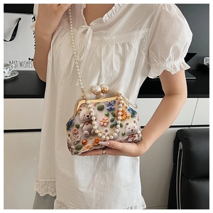 Detail of mini shell bag with knitted bear decor and elegant pearl chain shoulder strap