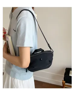 Détail du sac bandoulière en nylon noir avec double zip et sangle réglable sur mannequin