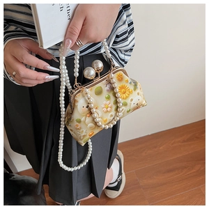 Detailed view of the pearl clasp and vintage floral embroidery on the shell bag