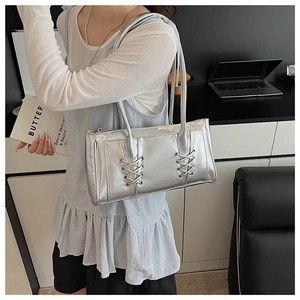 Détail du sac à bandoulière argenté métallisé avec sangles croisées dans un décor de bureau chic