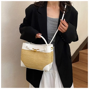 Detail of woven straw bag featuring white leather trim and golden knot buckle ornament