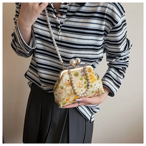 Detail of floral bear embroidery and large pearl clasp on the yellow seashell bag