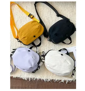 Sacs bandoulière légers en nylon jaune, noir, violet et blanc présentés sur un tapis