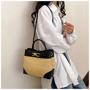 Detail of woven straw and black leather bucket bag with metallic twist lock and strap