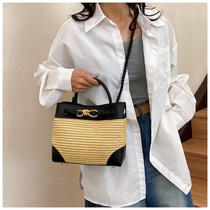 Detail of woven straw handbag with black leather trim and elegant gold buckle closure