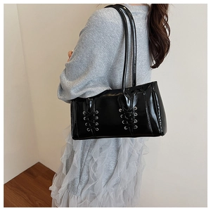 Détail du sac sous l'aisselle noir brillant avec design à lacets et œillets argentés