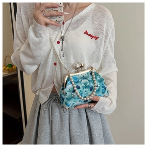 Detail of blue shell crossbody bag with cute bear patterns and elegant pearl chain handle
