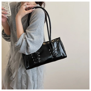 Détail du sac sous le bras en cuir verni noir avec laçage croisé décoratif