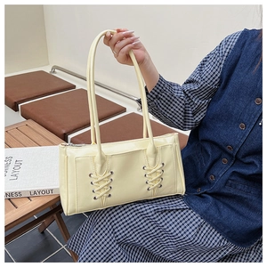 Sac baguette en cuir verni jaune pâle avec détails lacés, œillets et doubles bandoulières