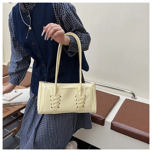 Détail du sac cabas en cuir jaune brillant avec un design élégant à lacets croisés sur le devant
