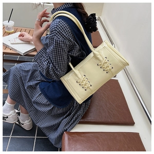 Détail du sac sous le bras jaune clair avec laçage croisé unique et bandoulière en cuir