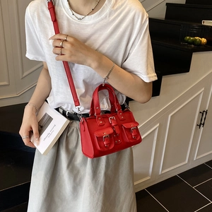 Red pebbled leather handbag with twin front pockets and buckles in a chic biker style