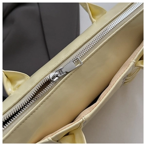 Gros plan sur la fermeture éclair argentée d'un sac cabas en cuir crème aux coutures fines