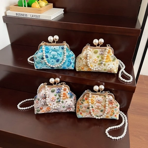 Cute crossbody shell bag with knitted bear and floral decor on wooden display