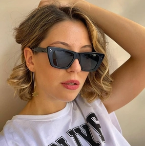 Detail view of black square sunglasses with three metal rivets on a female model