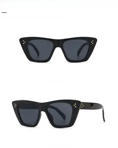 Detail of cat eye sunglasses with thick black frames and gold triple rivet accents