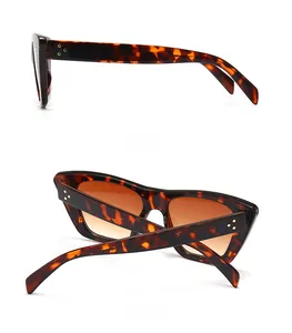 Detail view of tortoiseshell cat-eye sunglasses with gold triple dot accents and brown lenses
