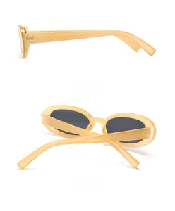 Detail view of oval retro sunglasses with cream yellow frames and dark tinted lenses