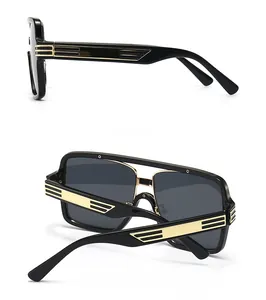 Detail of oversized black sunglasses with golden striped accents on the side temples