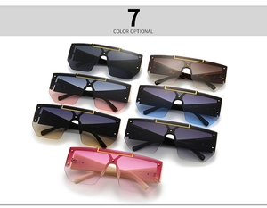 Flat lay of oversized shield sunglasses in seven colors with gold rivet accents