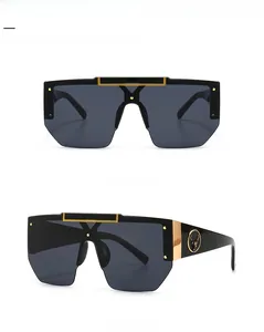 Detail view of black oversized shield sunglasses with gold bar and deer logo on temples