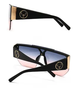 Detail view of square sunglasses with gold deer head logo and blue pink gradient lenses