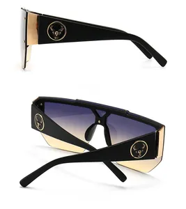 Detail of square oversized sunglasses with gold trim and metallic deer head logo