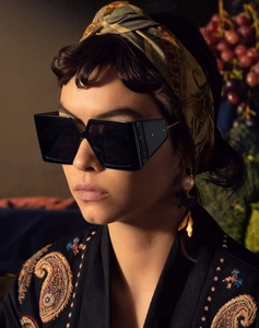Detail of classic square sunglasses featuring embossed brand lettering on the black temples