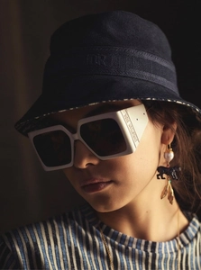 Detail of trendy square sunglasses and fisherman hat with luxury brand letters