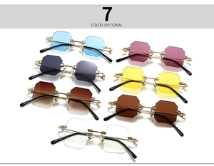 Flat lay of seven colorful rimless octagonal sunglasses with gold metal frames