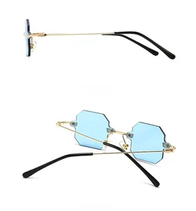 Detail view of gold metal temples and blue octagonal rimless lenses of the sunglasses