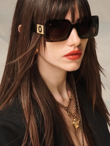 Close-up of retro square tortoise sunglasses featuring gold Medusa emblem on temples