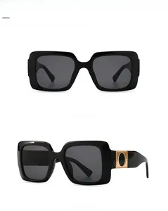 Detail view showing black square sunglasses with decorative gold metal hinge accents