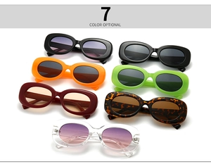 Seven pairs of vintage oval sunglasses displayed in diverse colors on white background