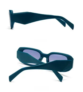 Detail view of dark green sunglasses showing geometric faceted frame and purple lenses