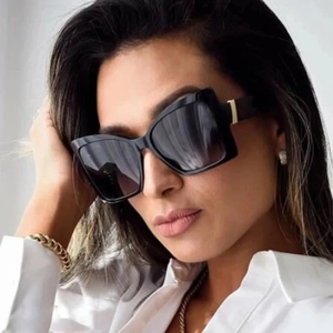 Close-up of square black sunglasses with gold metal hinges on a fashion model
