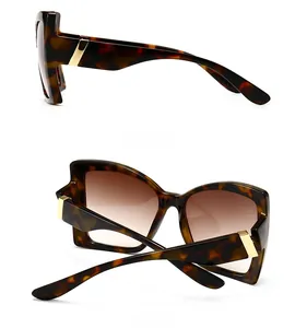 Detail view of tortoiseshell sunglasses with brown gradient lenses and gold side metal décor