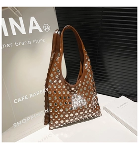 Detail of a brown leather tote bag featuring polished silver rivet studs in a grid pattern