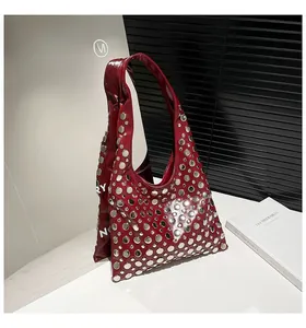 Detail of dark red patent leather hobo bag with polished silver metal rivets