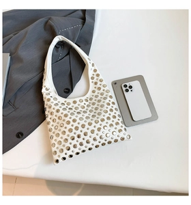 Detail view of a white crescent hobo bag with silver metallic rivets and minimalist design