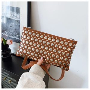 Detail of a brown leather shoulder bag featuring dense silver metal stud decorations