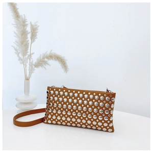 Detail of caramel brown leather shoulder bag with silver studs and slim strap