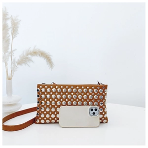 Close-up of caramel PU leather bag with silver studs showing size scale next to phone