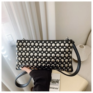 Close-up of black rectangular crossbody bag with silver punk-style metal rivets and strap