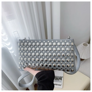 Detailed shot of a grey punk-style shoulder bag featuring silver metal rivets and strap