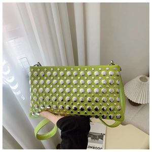 Detail of bright green punk style PU leather bag with large silver round studs and strap
