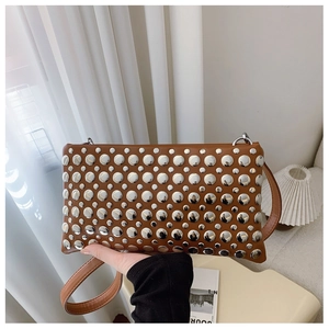 Detail of a brown leather handbag with silver metal studs and thin shoulder strap